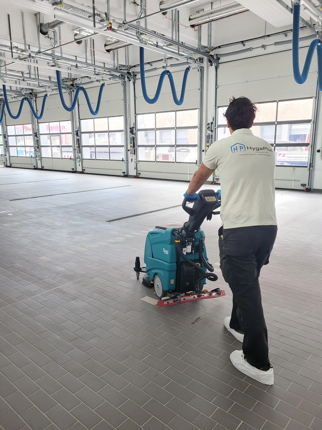 HygaPlus-Mitarbeiter bei der Bodenreinigung in einer Gewerbehalle