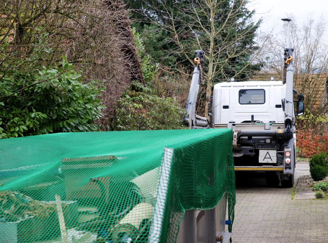 Absetzcontainer mit grünem Netz und Transportfahrzeug