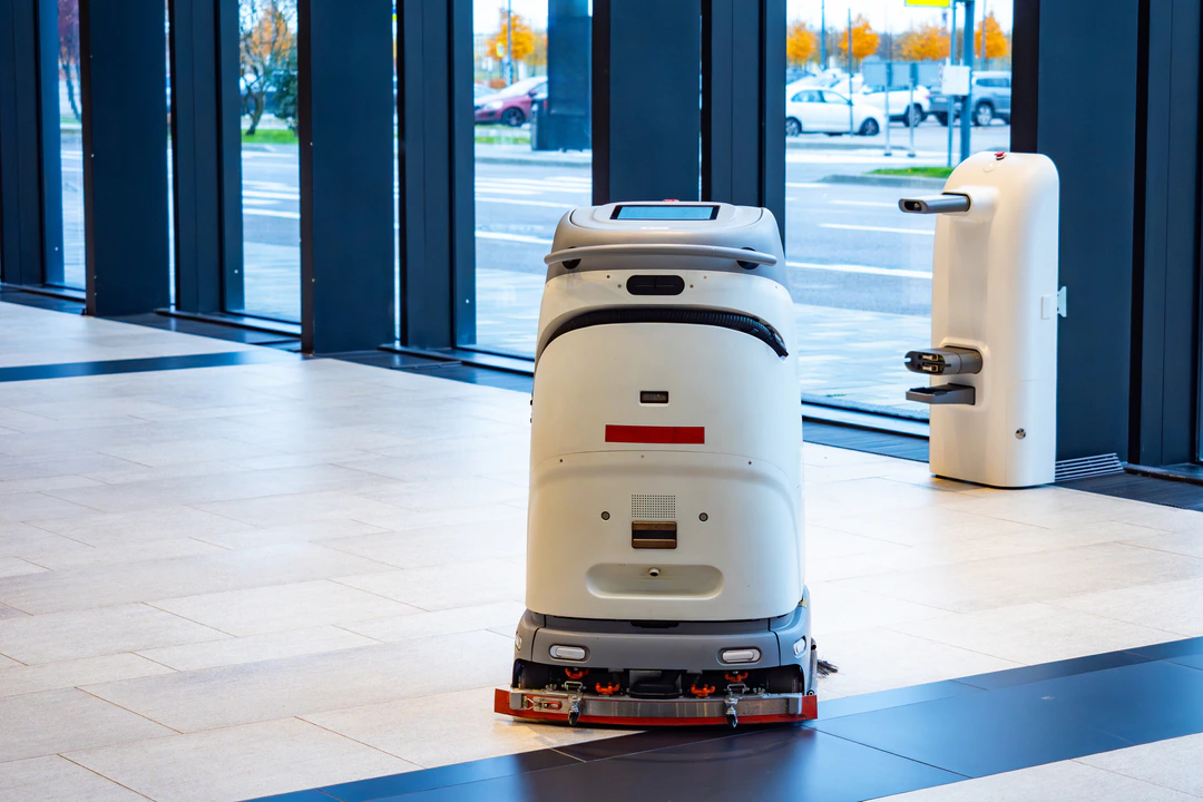 Gewerblicher Bodenreinigungsroboter auf einer freien Innenraumfläche; ergänzendes Robotikmotiv, keine Verfügbarkeitszusage